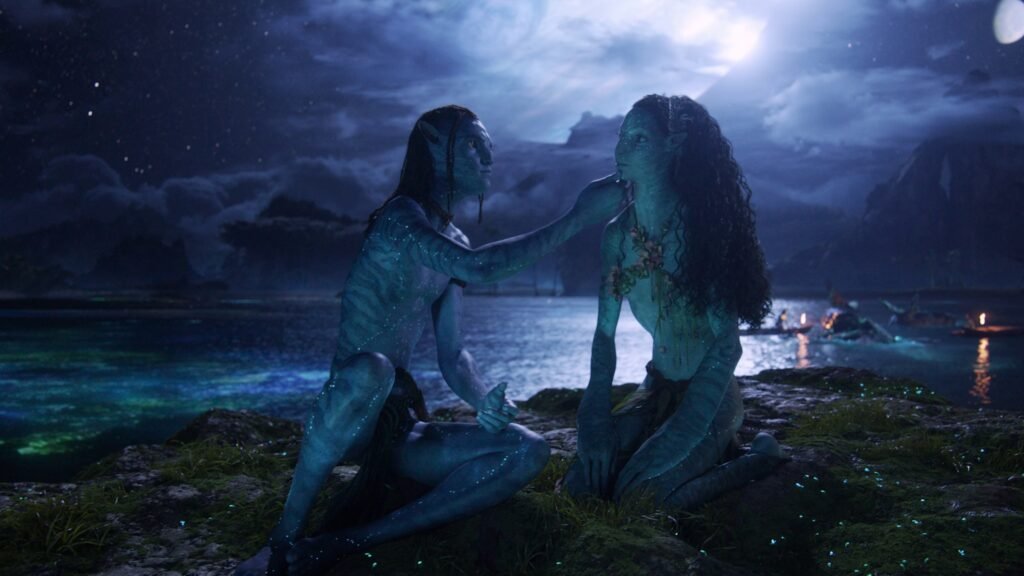 Showing NaVi Man and woman sitting on the beach in the moonlight image from Avatar Fire and Ash.Image Credit: Β© TMDb (www.themoviedb.org) β Used for informational/review purposes
